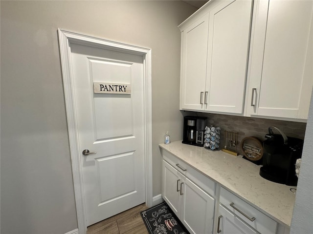 interior space featuring white cabinetry, decorative backsplash, light stone counters, and light wood-type flooring