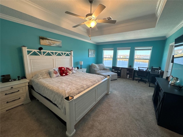 carpeted bedroom featuring ceiling fan, ornamental molding, a tray ceiling, and a textured ceiling