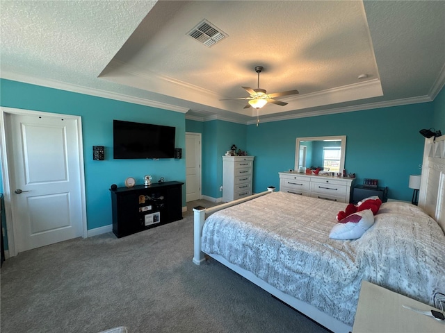 carpeted bedroom with a tray ceiling, ornamental molding, ceiling fan, and a textured ceiling