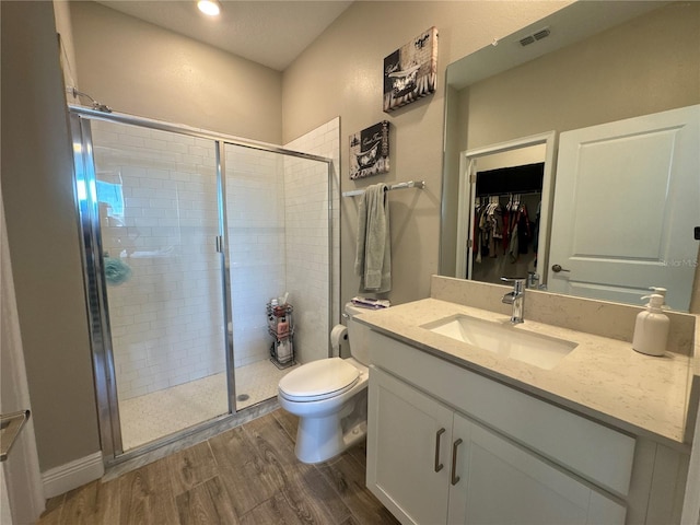 bathroom featuring wood-type flooring, toilet, an enclosed shower, and vanity