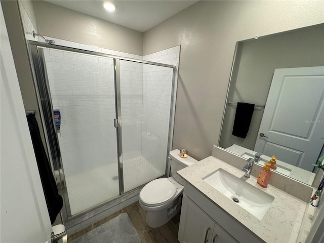 bathroom featuring vanity, toilet, a shower with shower door, and hardwood / wood-style floors