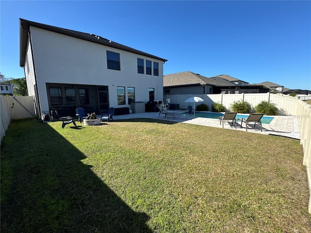 back of property with a patio, a yard, a fenced in pool, and a fire pit