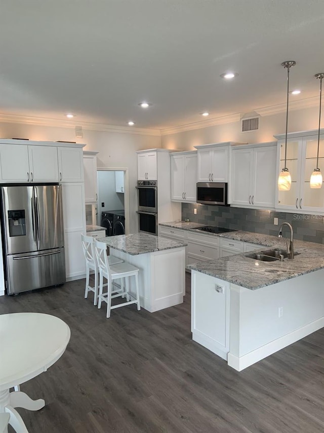 kitchen featuring decorative light fixtures, white cabinetry, backsplash, washing machine and clothes dryer, and stainless steel appliances