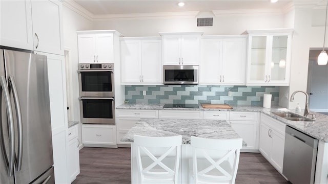 kitchen with sink, hanging light fixtures, appliances with stainless steel finishes, white cabinets, and backsplash