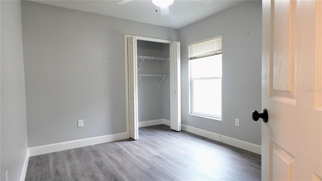 unfurnished bedroom with hardwood / wood-style flooring, a closet, and ceiling fan