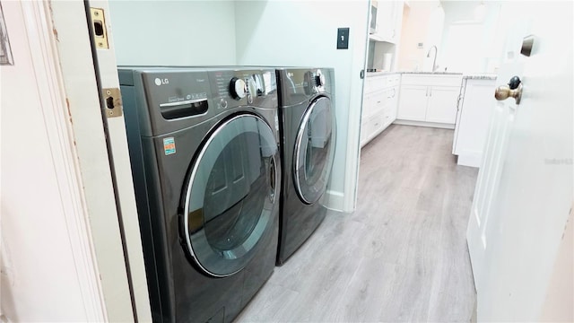 washroom with sink, washing machine and clothes dryer, and light wood-type flooring