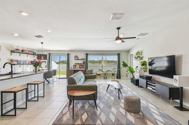 tiled living room with sink, a textured ceiling, and ceiling fan