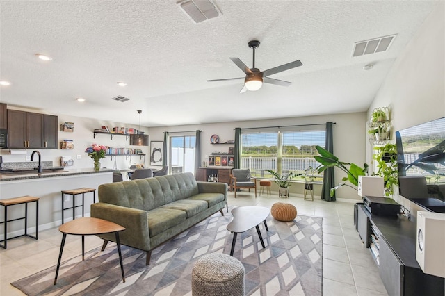 tiled living room featuring sink, a textured ceiling, and ceiling fan