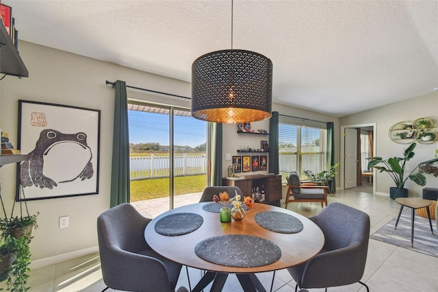 dining space featuring a wealth of natural light, a textured ceiling, and a water view