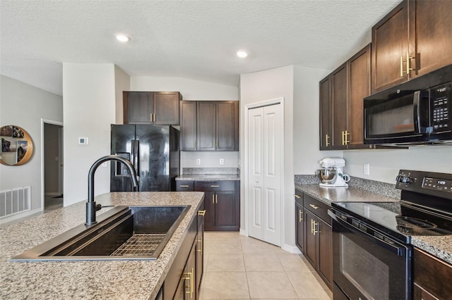 kitchen with light tile patterned flooring, dark brown cabinetry, sink, a textured ceiling, and black appliances