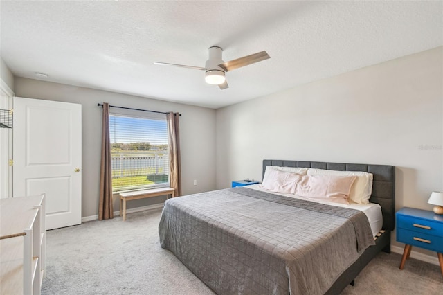 carpeted bedroom featuring ceiling fan and a textured ceiling