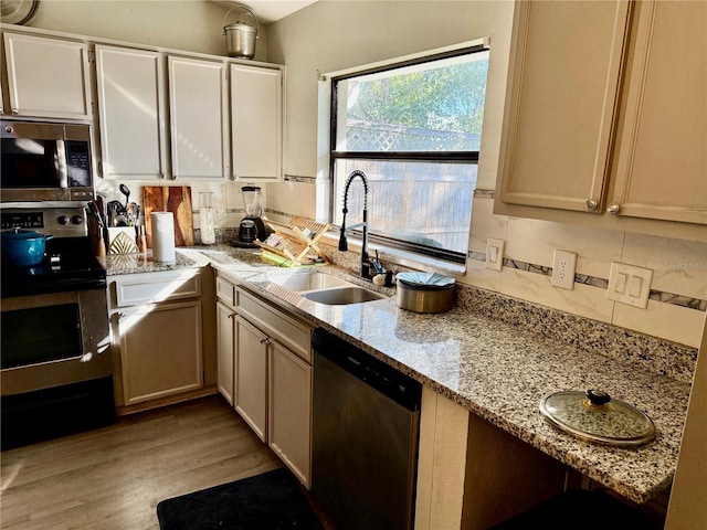 kitchen featuring sink, light hardwood / wood-style flooring, stainless steel appliances, and light stone countertops