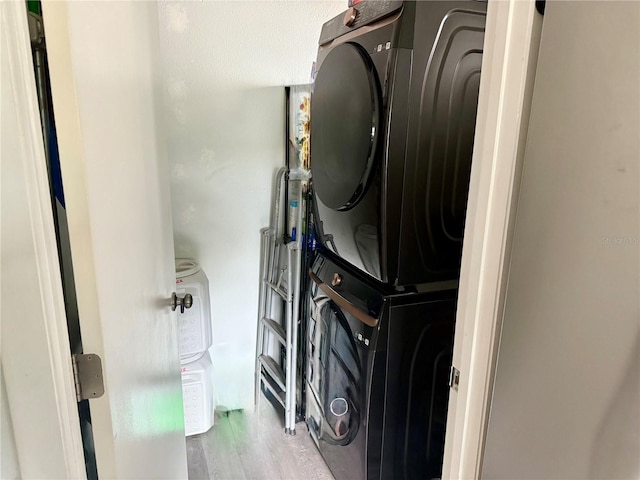 washroom with stacked washing maching and dryer and light wood-type flooring