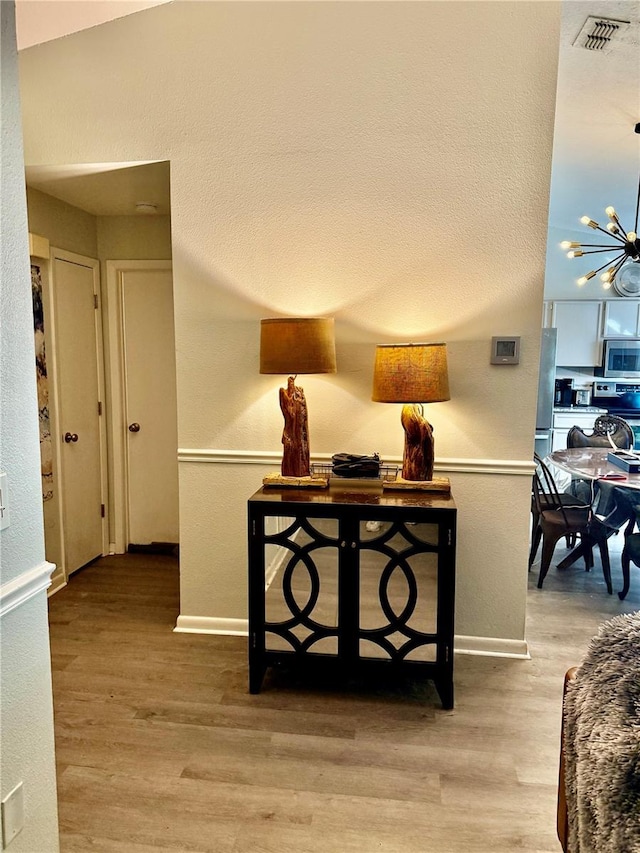 hallway with light hardwood / wood-style flooring and a chandelier