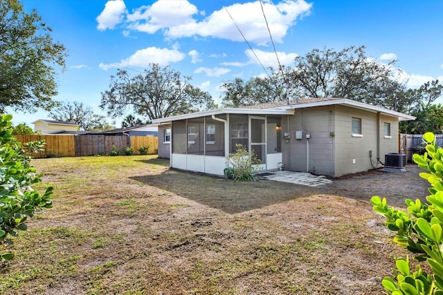 rear view of property featuring central AC, a sunroom, and a lawn