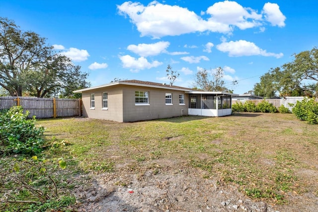 back of house with a sunroom and a lawn