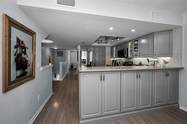 kitchen with light stone counters, stainless steel appliances, gray cabinets, and kitchen peninsula