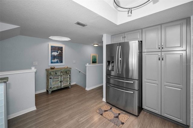 kitchen with stainless steel refrigerator with ice dispenser, hardwood / wood-style floors, and a textured ceiling