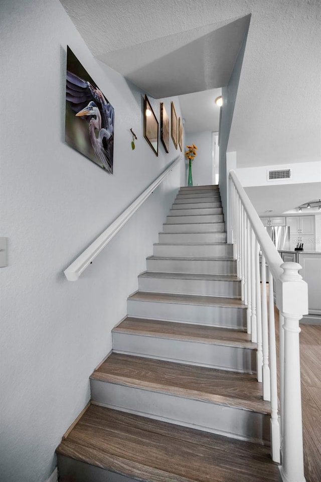 stairway featuring hardwood / wood-style floors and a textured ceiling