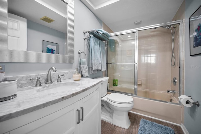 full bathroom featuring hardwood / wood-style flooring, vanity, bath / shower combo with glass door, and toilet