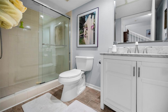 bathroom featuring toilet, vanity, and a shower with shower door