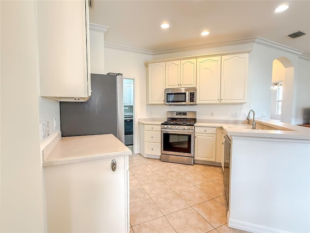 kitchen with sink, crown molding, light tile patterned floors, kitchen peninsula, and stainless steel appliances