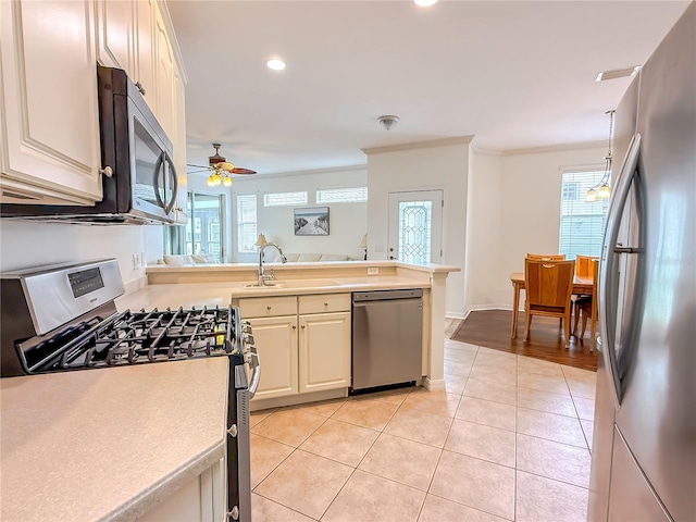 kitchen featuring sink, appliances with stainless steel finishes, hanging light fixtures, ornamental molding, and light tile patterned flooring