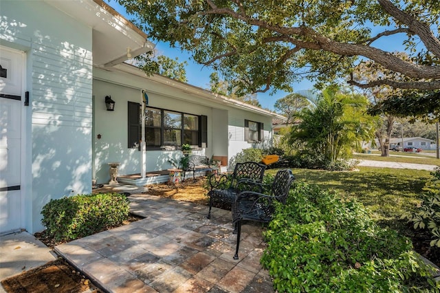 entrance to property featuring a yard and a patio area