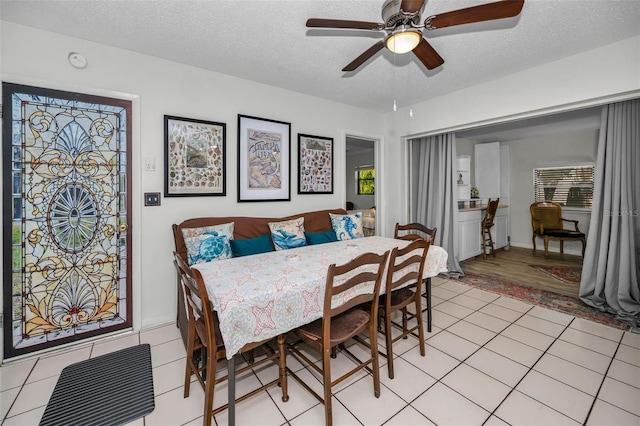 dining area with light tile patterned flooring, ceiling fan, and a textured ceiling