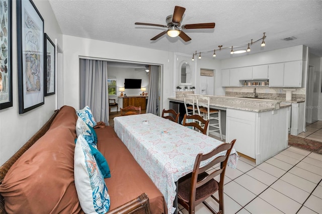 dining space featuring ceiling fan, sink, a textured ceiling, and light tile patterned flooring