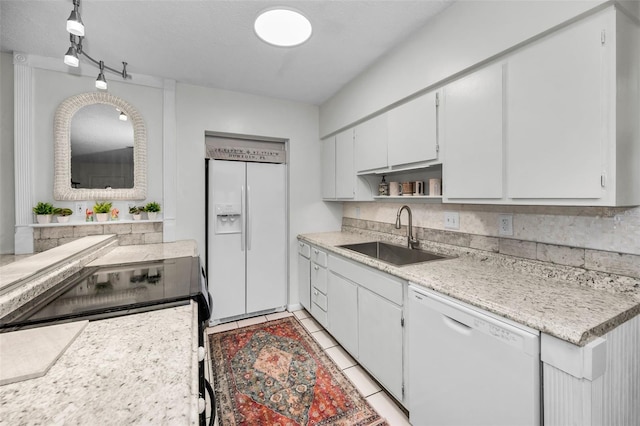 kitchen with rail lighting, sink, white cabinets, light tile patterned floors, and white appliances