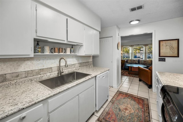 kitchen with sink, white cabinetry, light tile patterned floors, dishwasher, and decorative backsplash