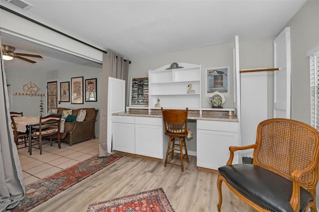 kitchen featuring light stone counters, ceiling fan, light hardwood / wood-style flooring, and white cabinets