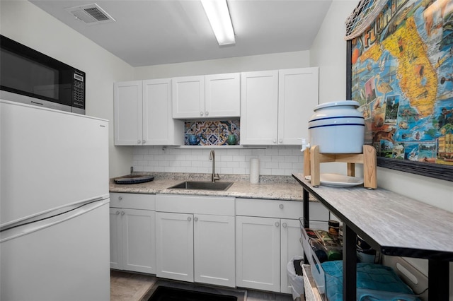 kitchen featuring white cabinetry, sink, tasteful backsplash, and white fridge