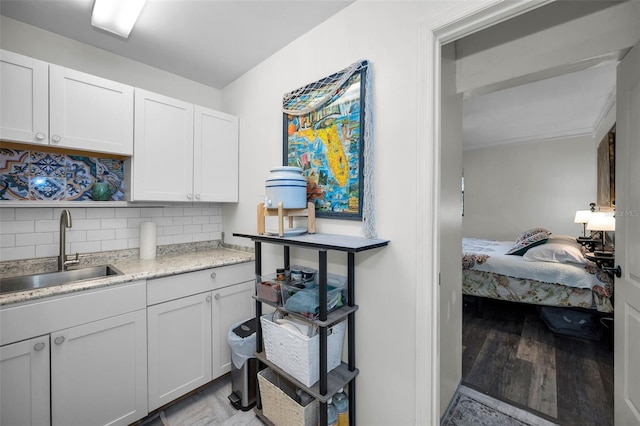 kitchen featuring light hardwood / wood-style floors, sink, decorative backsplash, and white cabinets