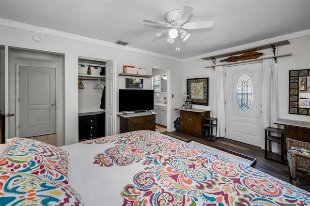 bedroom featuring ensuite bathroom, dark hardwood / wood-style flooring, ornamental molding, ceiling fan, and a closet