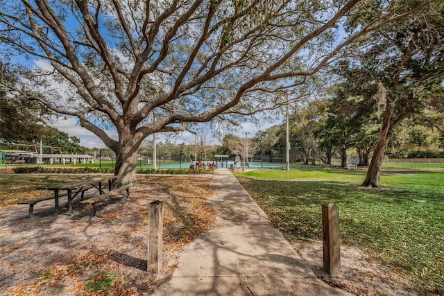 view of home's community featuring a tennis court, fence, and a lawn