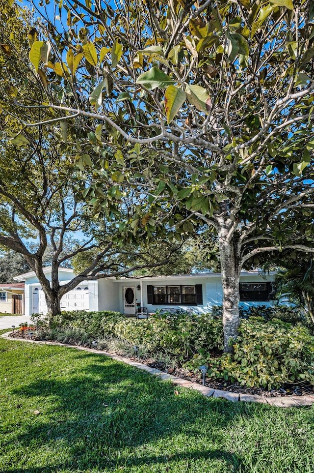 obstructed view of property with an attached garage and a front yard