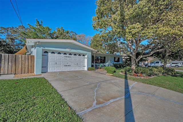 single story home featuring a front yard, driveway, an attached garage, and fence