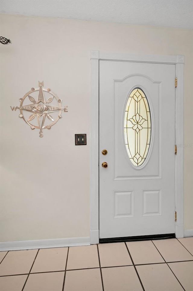 foyer entrance with light tile patterned floors and baseboards