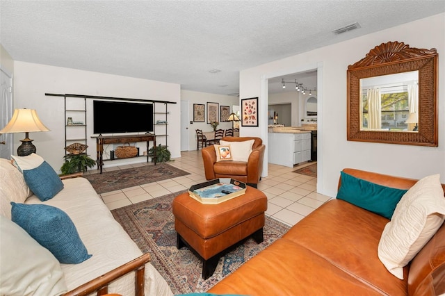 tiled living area with track lighting, visible vents, and a textured ceiling