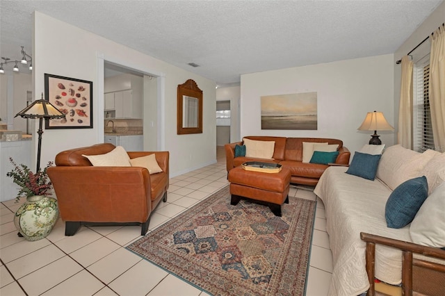 living room with visible vents, a textured ceiling, and light tile patterned floors