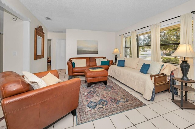 living room featuring a textured ceiling, light tile patterned floors, and visible vents