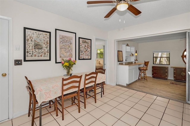 dining area with a healthy amount of sunlight, light tile patterned floors, ceiling fan, and a textured ceiling