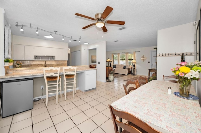 kitchen with light tile patterned floors, tasteful backsplash, visible vents, freestanding refrigerator, and a textured ceiling