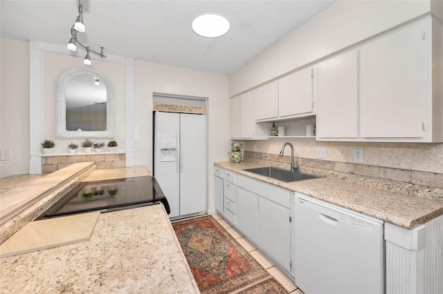 kitchen with light tile patterned floors, white appliances, a sink, white cabinets, and light countertops