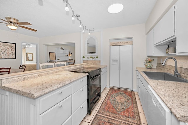 kitchen with white appliances, white cabinets, a ceiling fan, a peninsula, and a sink