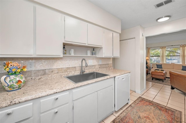 kitchen with open shelves, visible vents, white cabinets, white dishwasher, and a sink