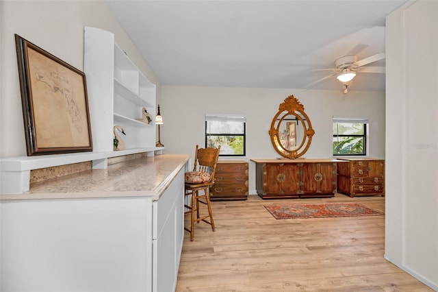 interior space with light wood finished floors, open shelves, a wealth of natural light, and a kitchen breakfast bar