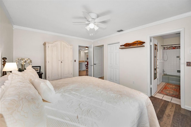 bedroom with two closets, visible vents, ornamental molding, and wood finished floors